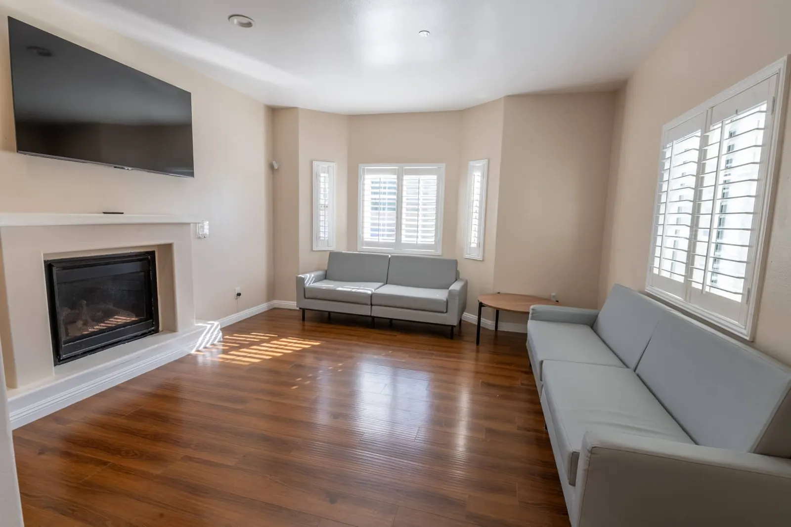 Bright, comfortable shared living room with a fireplace and wall-mounted television