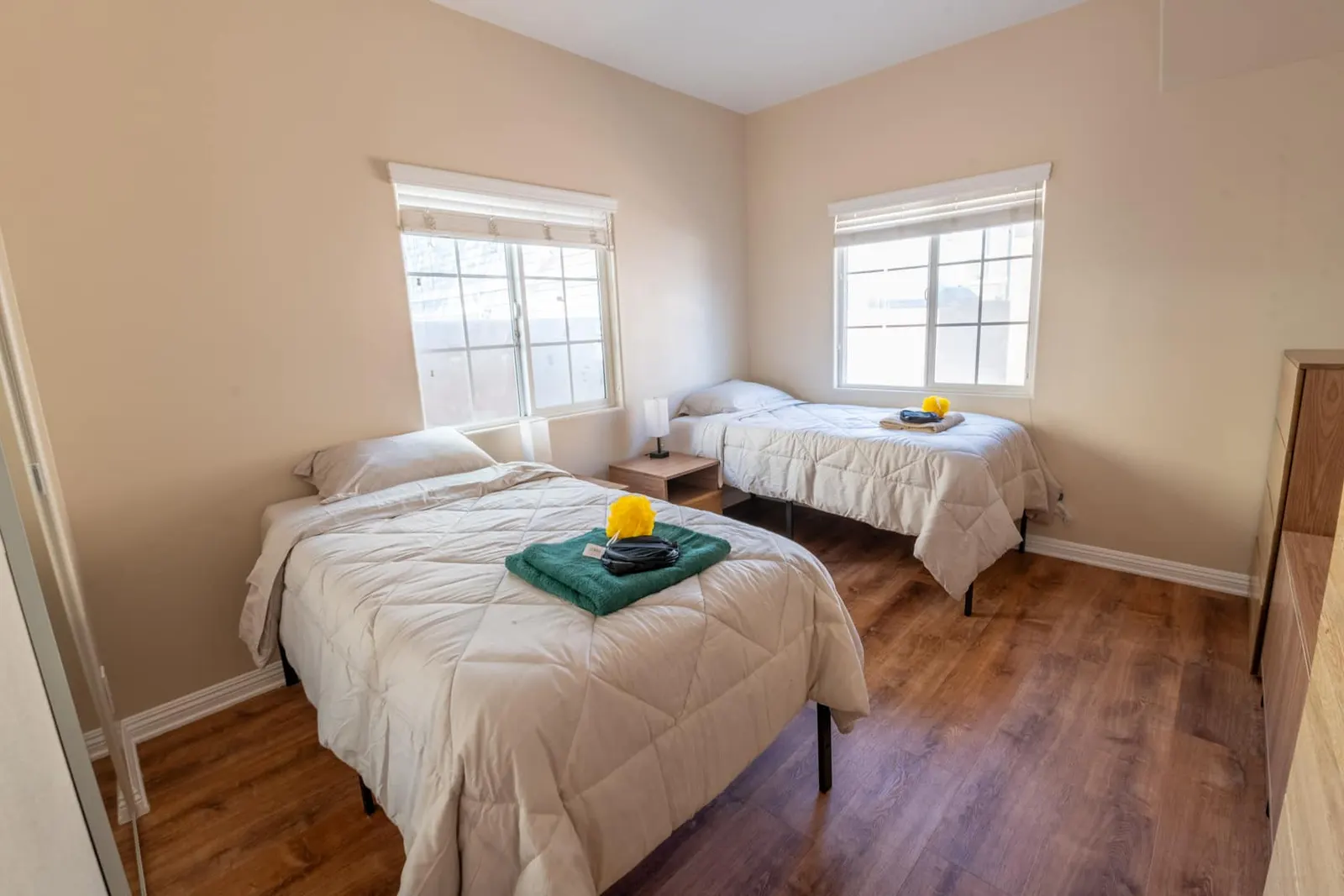 A bright, home-like bedroom with fresh linens and welcome amenities
