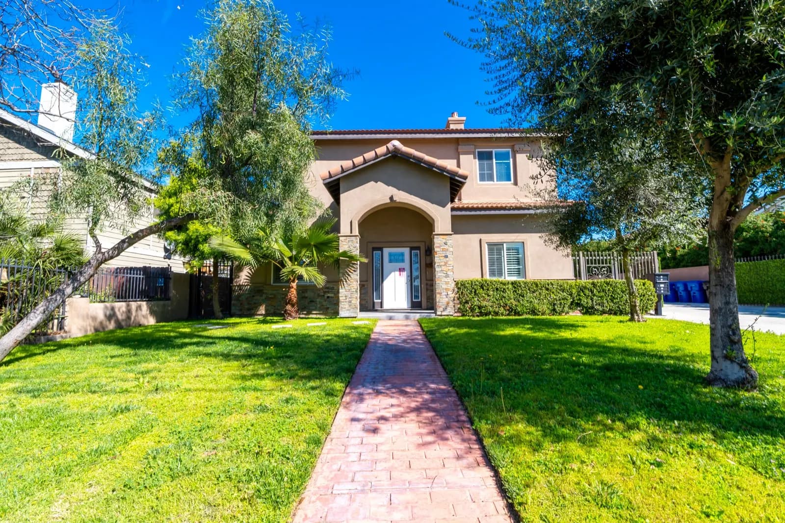 Brick walkway leading to the arched front entrance across a green lawn